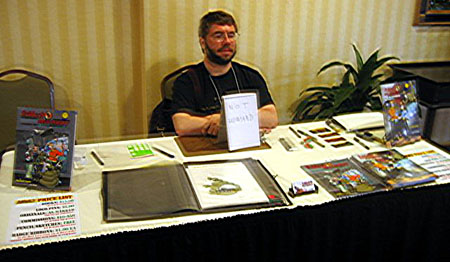 Paul Neubauer babysits Howard Tayler's Table at Penguicon 5.0